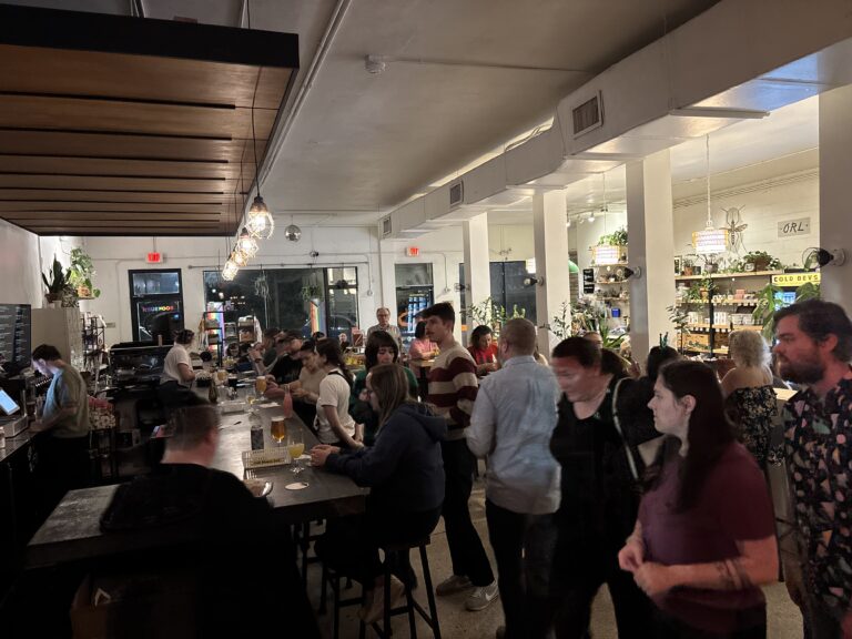 Crowded evening at BookBurn Café and Social in Orlando, with people gathered around the bar in a queer-inclusive community space.