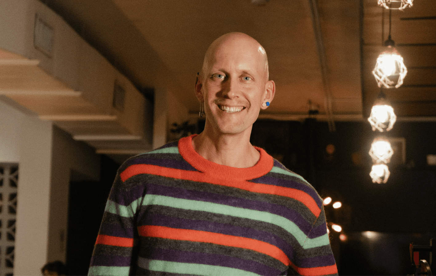 Justin standing inside BookBurn Cafe and Social in Orlando's Milk District with a smile and hands in his pockets.