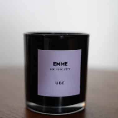 EMME New York City Ube candle in a black glass jar displayed on a table at BookBurn Cafe and Social