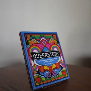 QueerStory infographic history of the fight for LGBTQ+ rights book displayed on a table at BookBurn Cafe and Social