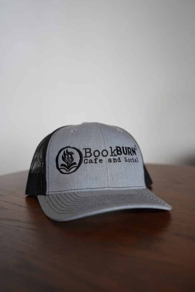 Gray and black BookBurn logo hat displayed at BookBurn Cafe in Orlando