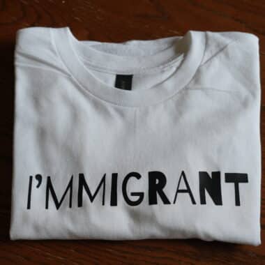 Folded white ‘I’m Immigrant’ statement t-shirt displayed at BookBurn Cafe and Social in Orlando