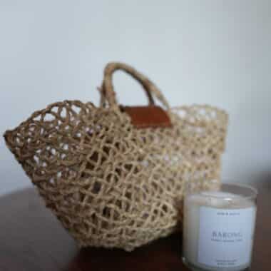 Handwoven basket tote bag displayed next to soy candle at BookBurn Cafe in Orlando