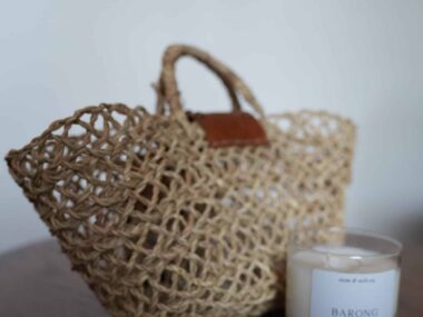 Handwoven basket tote bag displayed next to soy candle at BookBurn Cafe in Orlando