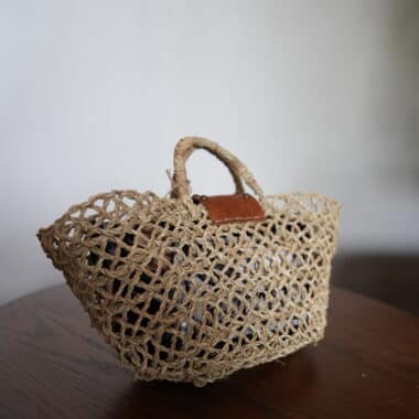 Handwoven open weave market basket tote with leather detail displayed at BookBurn Cafe in Orlando