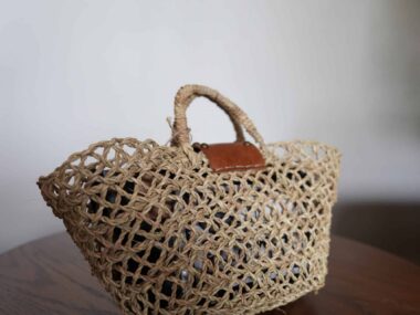 Handwoven open weave market basket tote with leather detail displayed at BookBurn Cafe in Orlando