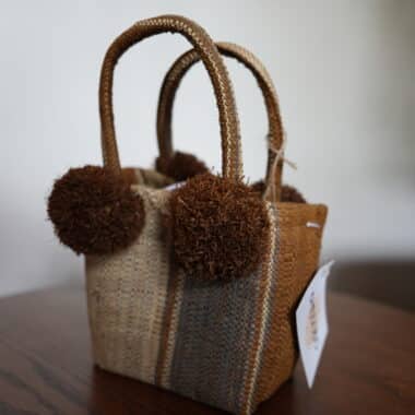 Handwoven mini tote bag with pom pom accents displayed at BookBurn Cafe in Orlando