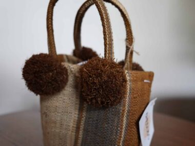 Handwoven mini tote bag with pom pom accents displayed at BookBurn Cafe in Orlando
