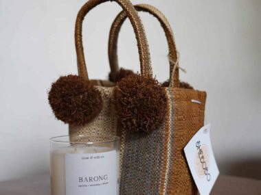 Handwoven mini tote bag with pom pom accents next to soy candle at BookBurn Cafe in Orlando
